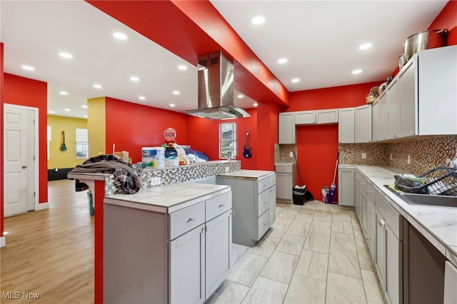 kitchen with gray cabinets, exhaust hood, tasteful backsplash, and sink