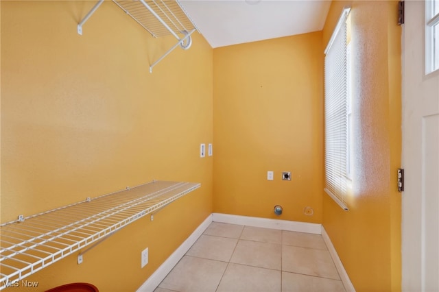 laundry area with electric dryer hookup and light tile patterned flooring