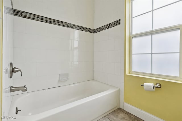 bathroom featuring tiled shower / bath combo, a healthy amount of sunlight, and tile patterned flooring