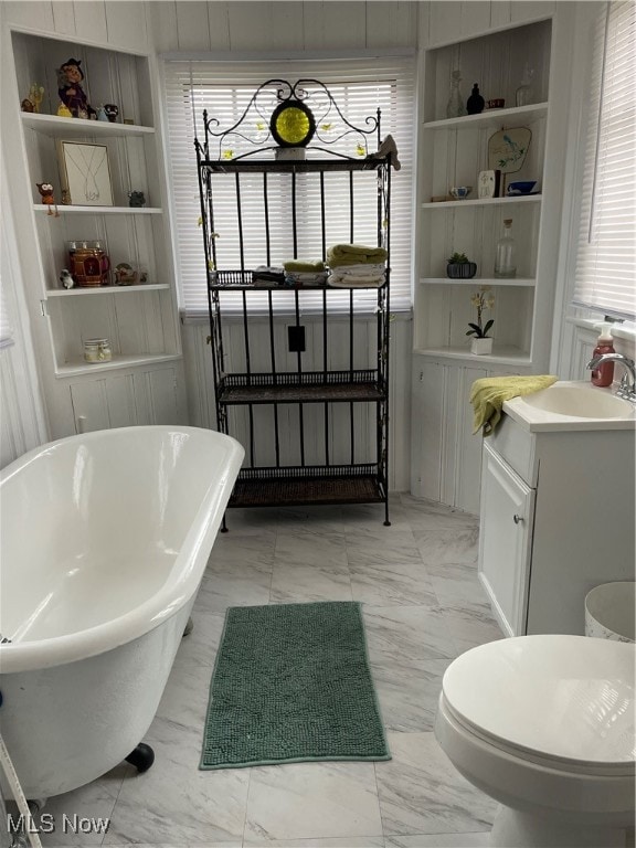 bathroom featuring a tub to relax in, vanity, toilet, and a wealth of natural light