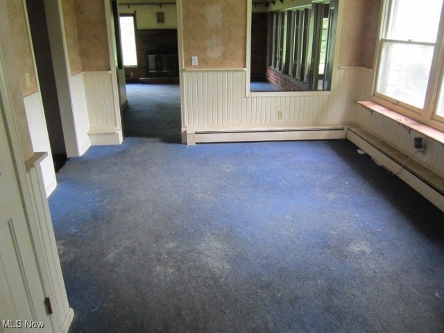 carpeted spare room with a baseboard heating unit