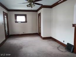 carpeted empty room with ceiling fan and crown molding