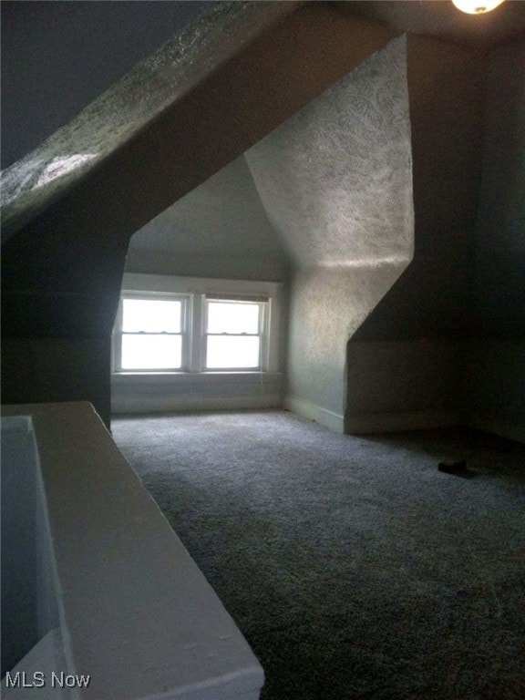 bonus room featuring lofted ceiling, carpet flooring, and a textured ceiling