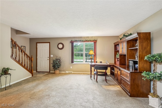 carpeted home office featuring a textured ceiling