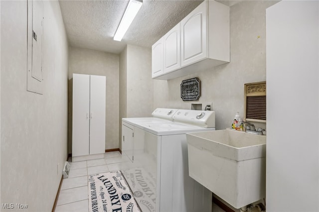 clothes washing area featuring cabinets, sink, washer and dryer, light tile patterned floors, and a textured ceiling