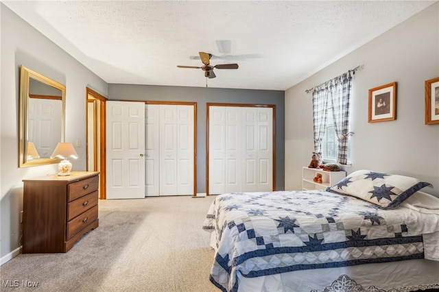 carpeted bedroom with two closets, ceiling fan, and a textured ceiling