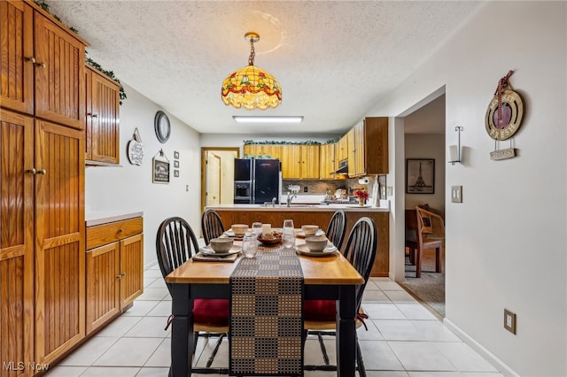 dining space featuring sink, light tile patterned floors, and a textured ceiling