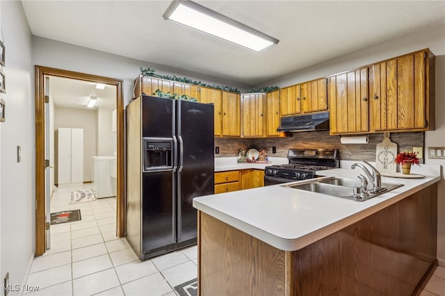 kitchen featuring sink, backsplash, kitchen peninsula, light tile patterned floors, and black appliances