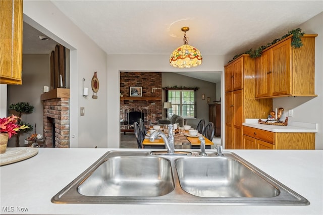 kitchen with a fireplace, pendant lighting, vaulted ceiling, and sink