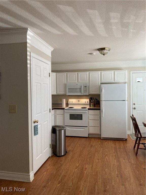 kitchen with a textured ceiling, white appliances, wood-type flooring, ornamental molding, and white cabinets