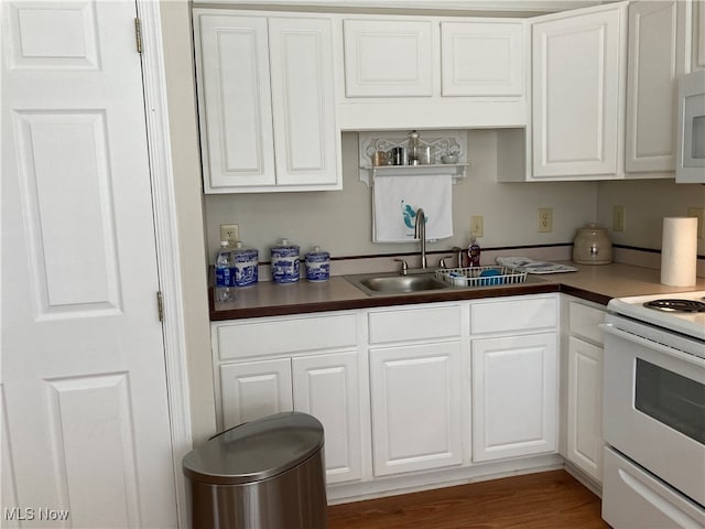 kitchen featuring white cabinetry, white appliances, dark hardwood / wood-style flooring, and sink