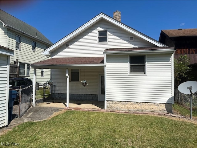 rear view of property featuring a patio, a chimney, a yard, and fence