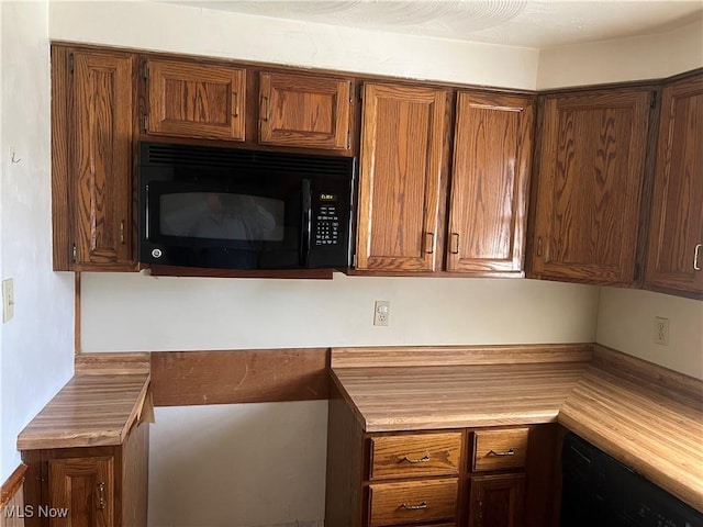 kitchen with brown cabinetry, black appliances, and light countertops