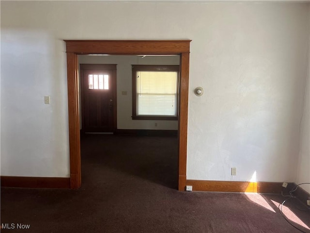 interior space featuring baseboards and dark carpet