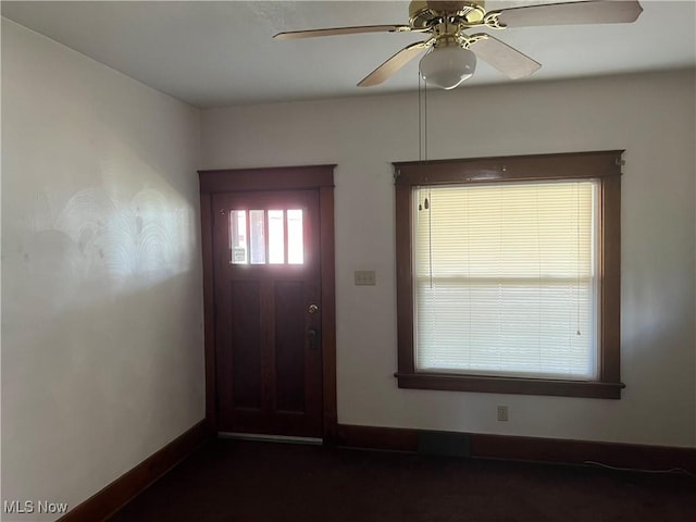 foyer entrance featuring a ceiling fan and baseboards