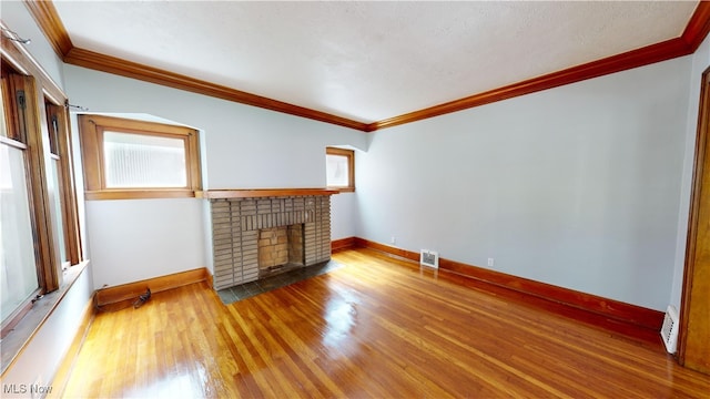 unfurnished living room featuring a textured ceiling, ornamental molding, hardwood / wood-style flooring, and a fireplace