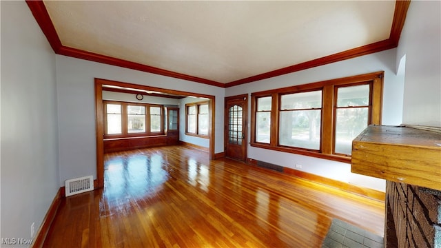 unfurnished living room with hardwood / wood-style flooring and crown molding