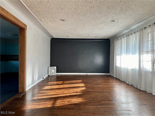 spare room featuring dark hardwood / wood-style floors and a textured ceiling