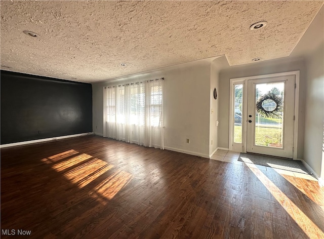 foyer entrance with hardwood / wood-style floors, plenty of natural light, and a textured ceiling