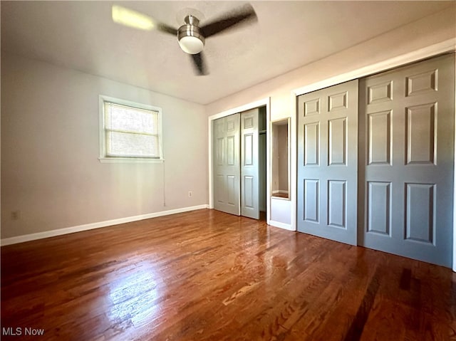 unfurnished bedroom with two closets, ceiling fan, and hardwood / wood-style flooring