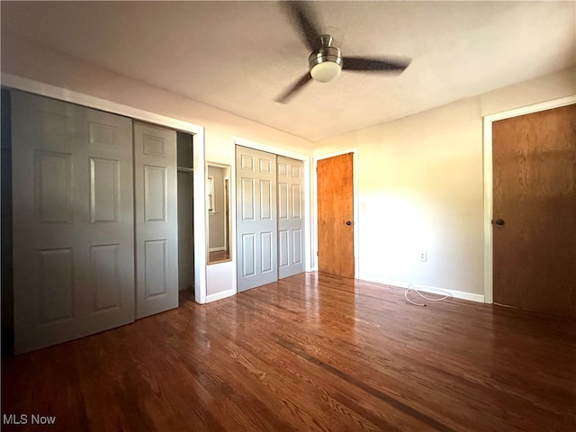 unfurnished bedroom with multiple closets, ceiling fan, and dark hardwood / wood-style floors