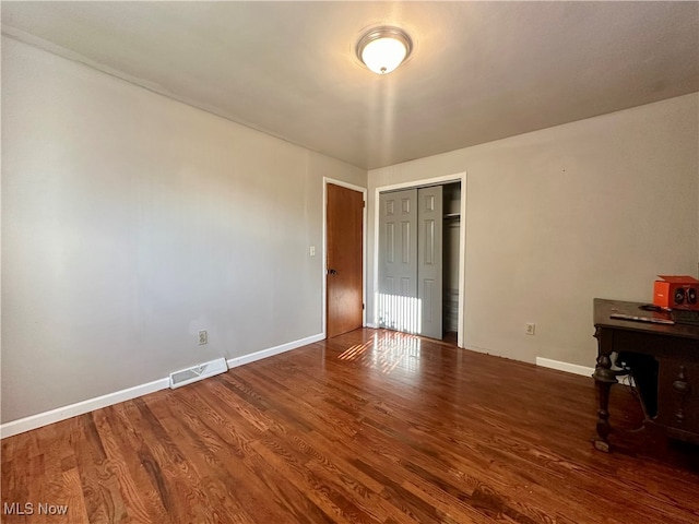 unfurnished bedroom with dark hardwood / wood-style floors and a closet