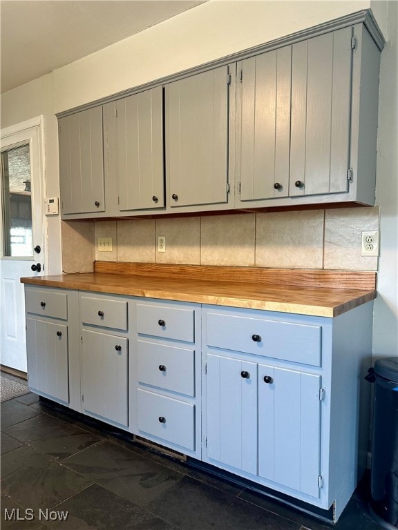 kitchen featuring gray cabinetry, butcher block countertops, and backsplash