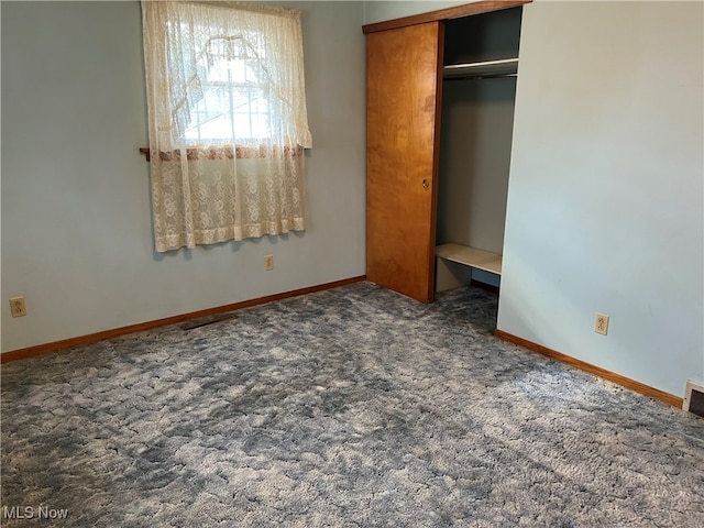 unfurnished bedroom featuring dark carpet and a closet