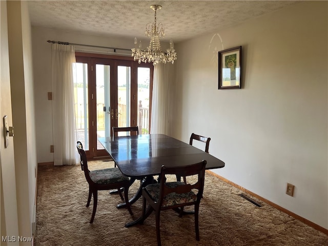 dining space featuring a textured ceiling, a notable chandelier, carpet floors, and french doors