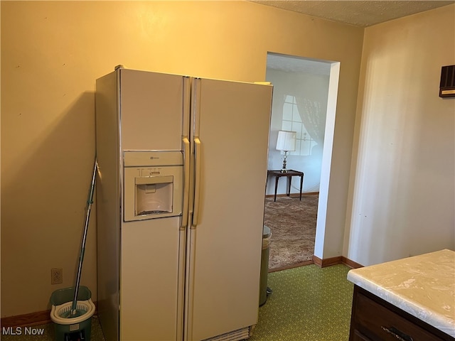 kitchen with dark brown cabinets, white fridge with ice dispenser, and a textured ceiling