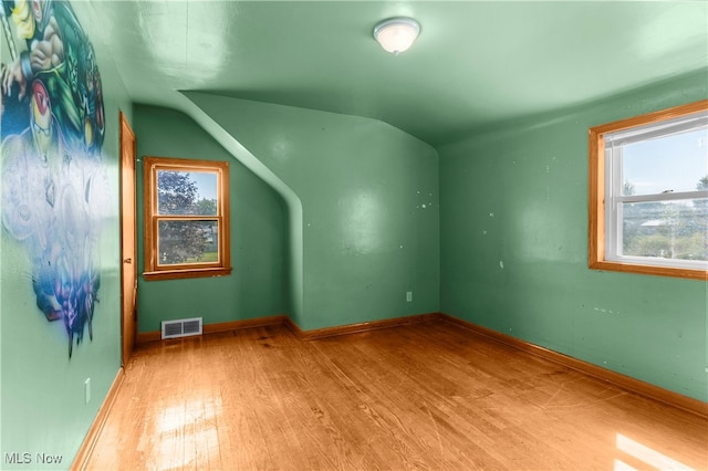 spare room featuring light hardwood / wood-style flooring and vaulted ceiling