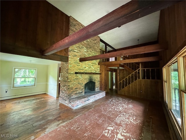 unfurnished living room featuring dark hardwood / wood-style flooring, baseboard heating, a brick fireplace, a towering ceiling, and beam ceiling