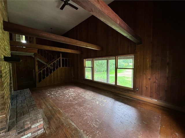 interior space with lofted ceiling, ceiling fan, wood walls, and a brick fireplace