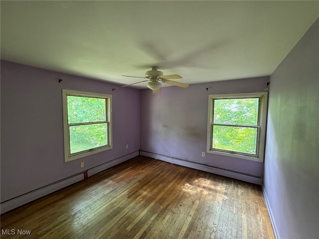 unfurnished room with a baseboard heating unit, ceiling fan, wood-type flooring, and a healthy amount of sunlight