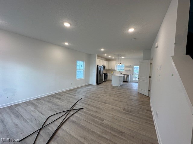 unfurnished living room featuring a wealth of natural light, light hardwood / wood-style flooring, and a textured ceiling