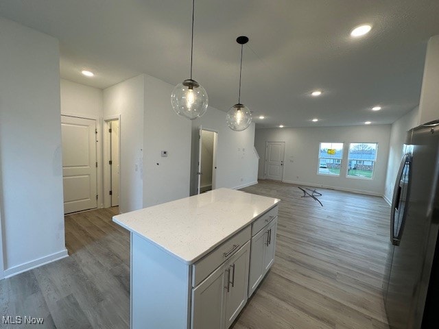 kitchen with a kitchen island, light hardwood / wood-style flooring, stainless steel fridge, pendant lighting, and white cabinets