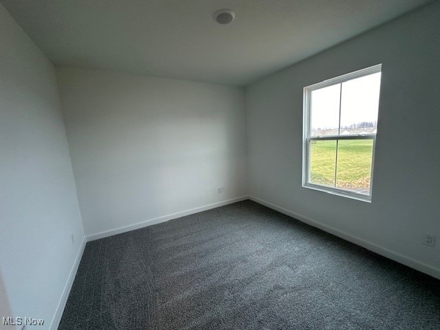 spare room featuring dark colored carpet