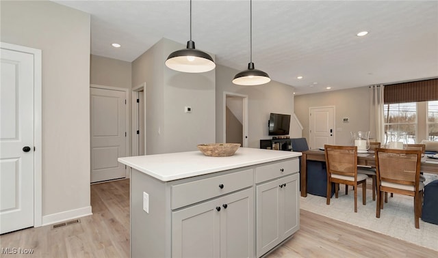 kitchen featuring decorative light fixtures, a kitchen island, and light hardwood / wood-style flooring