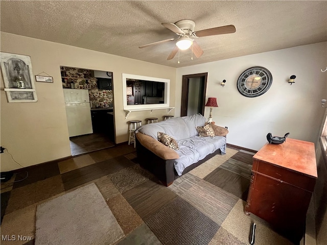 bedroom featuring white refrigerator, ceiling fan, and a textured ceiling