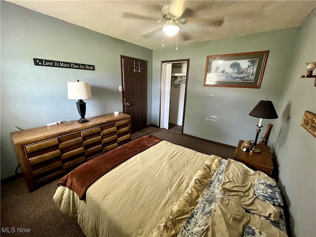 carpeted bedroom with a closet, ceiling fan, a walk in closet, and a textured ceiling