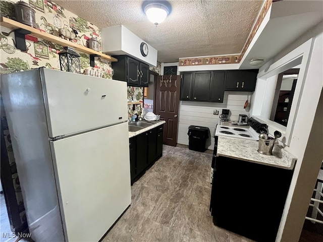 kitchen featuring a textured ceiling, sink, and white fridge