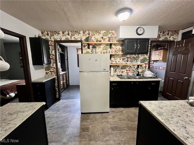 kitchen with a textured ceiling, white fridge, and sink