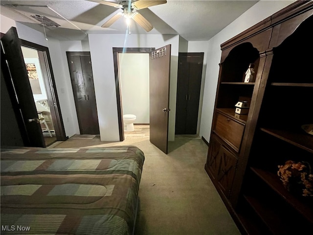 bedroom featuring ensuite bath, light colored carpet, and ceiling fan