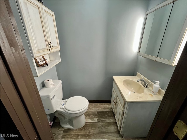 bathroom with wood-type flooring, toilet, and vanity