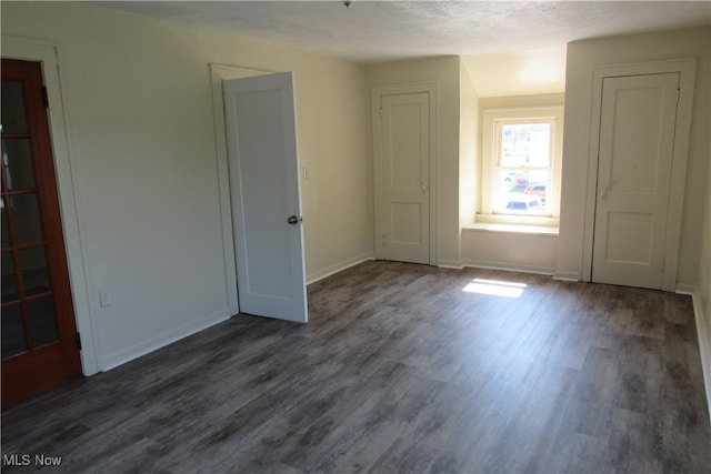 spare room featuring a textured ceiling and dark hardwood / wood-style floors