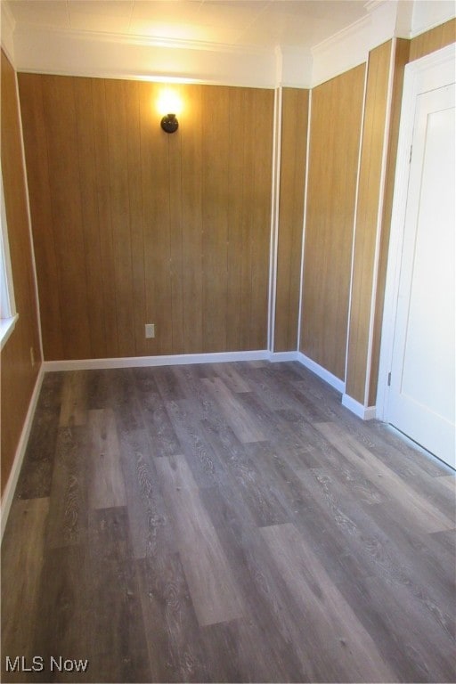 unfurnished room featuring crown molding, hardwood / wood-style flooring, and wooden walls