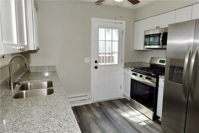 kitchen with a baseboard radiator, appliances with stainless steel finishes, dark wood-type flooring, ceiling fan, and white cabinets