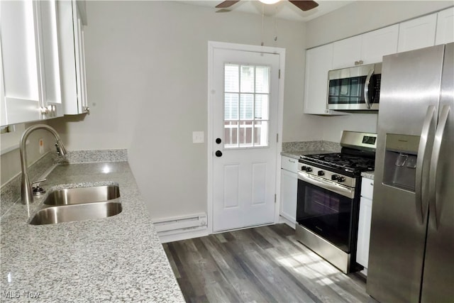 kitchen featuring appliances with stainless steel finishes, dark wood-type flooring, white cabinetry, a baseboard heating unit, and ceiling fan