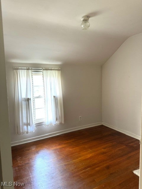 unfurnished room with vaulted ceiling and dark hardwood / wood-style flooring