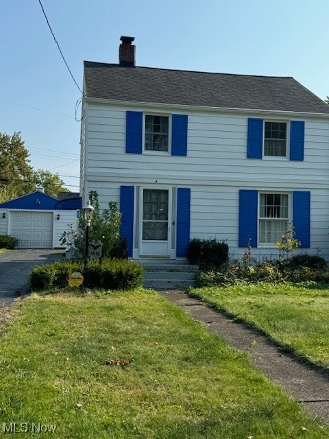 view of front of home featuring a garage, an outdoor structure, and a front yard